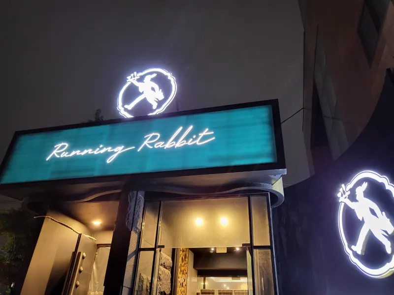 청록빛 Running Rabbit 간판과 토끼 로고